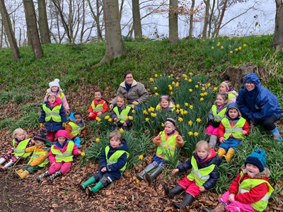 Children in sitting in grass with daffodils